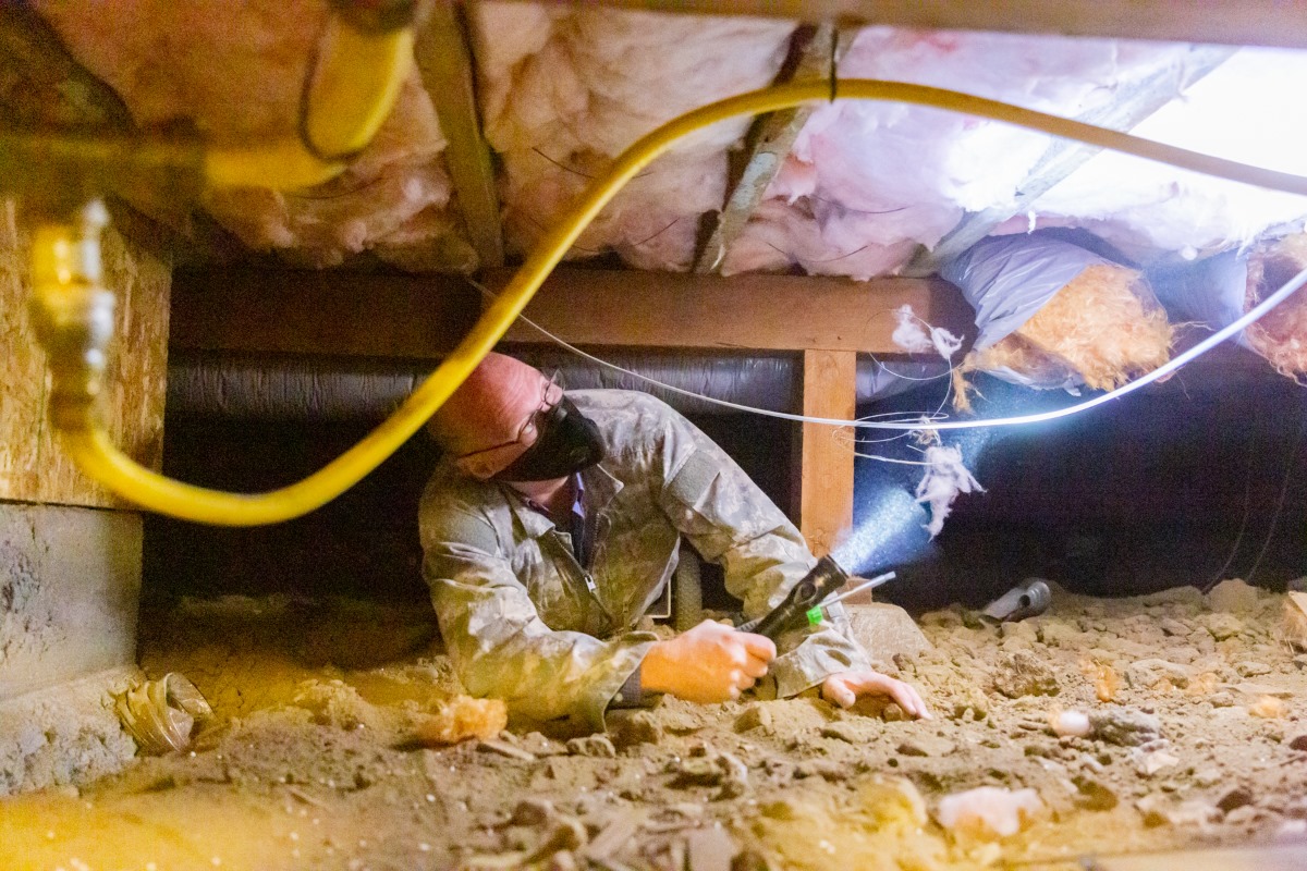David inspecting a crawlspace with a flashlight